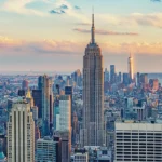 An aerial view of the Manhattan skyline, where the Empire State Building rises high above the skyscrapers