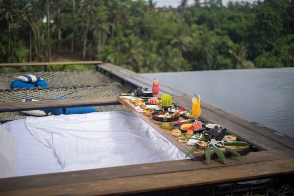 A hammock by the outdoor infinity pool at Kaamala Resort Ubud - Luxury Escapes 