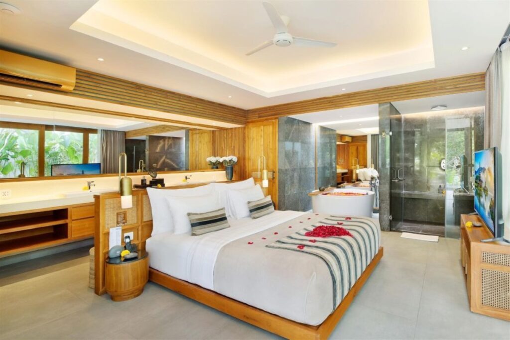 Interior of a private pool villa at Kamala Resort, filled with a king bed with romantic heart decor, deep soaking tub and granite rain shower - Luxury Escapes