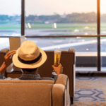 Man with a fedora hat enjoys a beer while at the airport lounge - Luxury Escapes