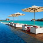 Luxury overwater villas in the Maldives with private sun loungers, umbrellas, and stunning ocean views, perfect for a relaxing adults-only getaway.