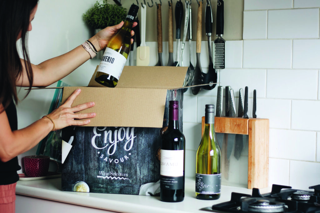 A woman opens a delivery from Wine Selectors - Luxury Escapes