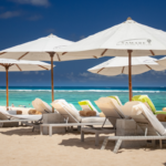 Shaded sunlounges on the beach at Samabe Bali Suites & Villas. Luxury Escapes.