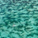 Person paddle boarding through the secluded water at Samabe Bali Suites & Villas. Luxury Escapes.