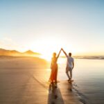 Couple walking along the beach on their destination wedding - Luxury Escapes.