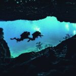 Scuba divers explore an underwater cave in Malta