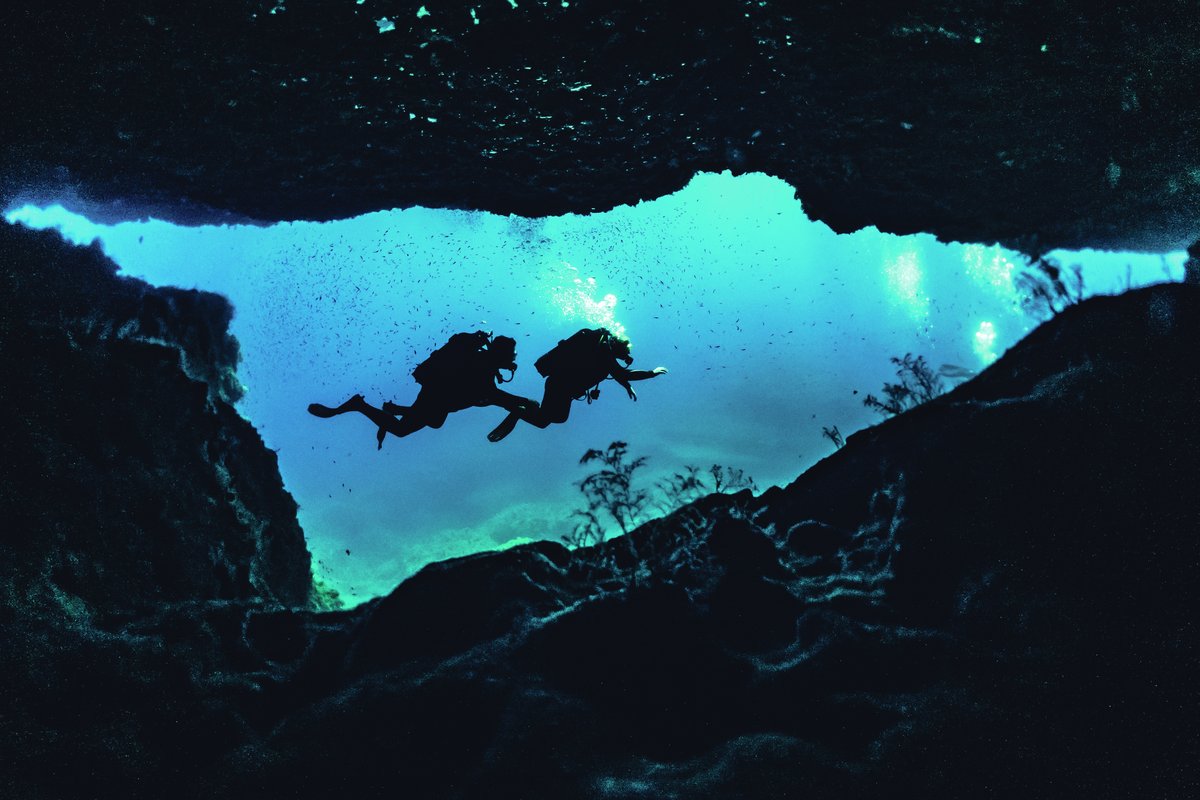 Scuba divers explore an underwater cave in Malta