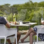 Couple sharing wine and dinner on a terrace at Pullman Bunker Bay Resort, Western Australia | Luxury Escapes.